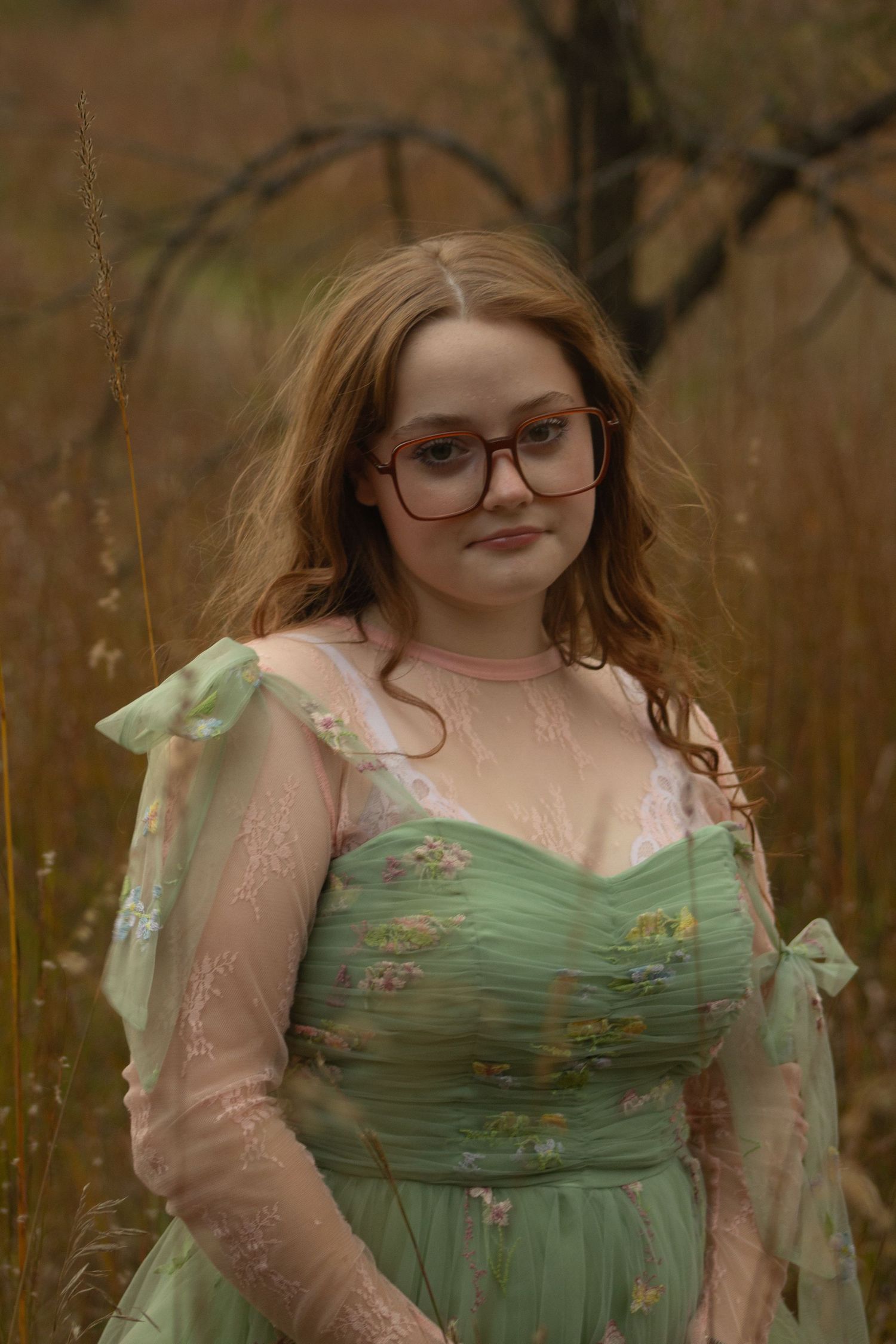 A vintage-inspired portrait featuring a mint green dress with floral details and sheer pink overlay in a natural outdoor setting.