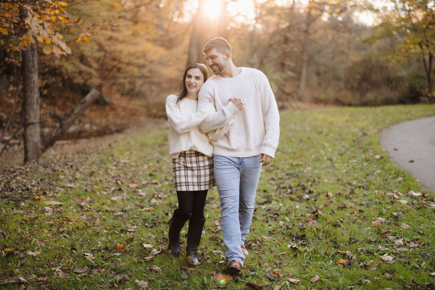 A couple walks together on a winding path through golden fall foliage.