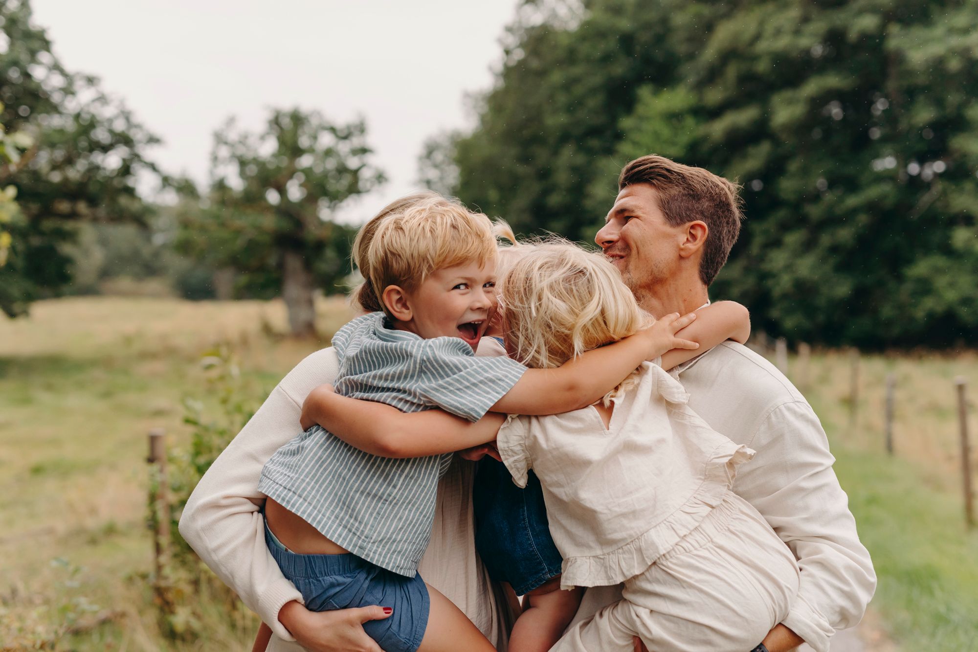 A loving family shares joyful embraces and laughter in a series of candid outdoor moments on a grassy field.