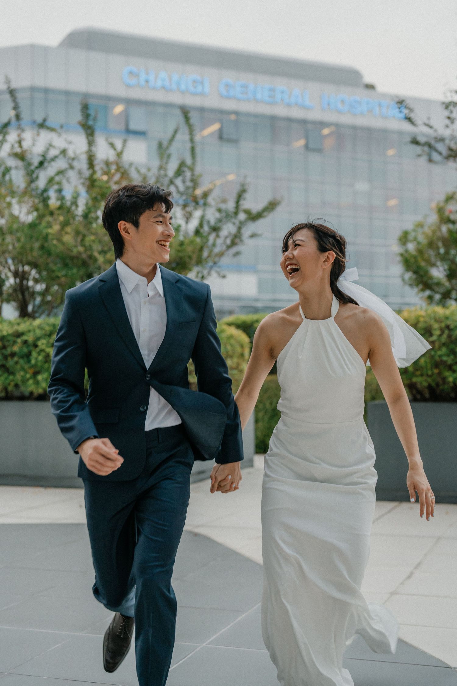 Happy couple runs hand in hand during wedding photoshoot.