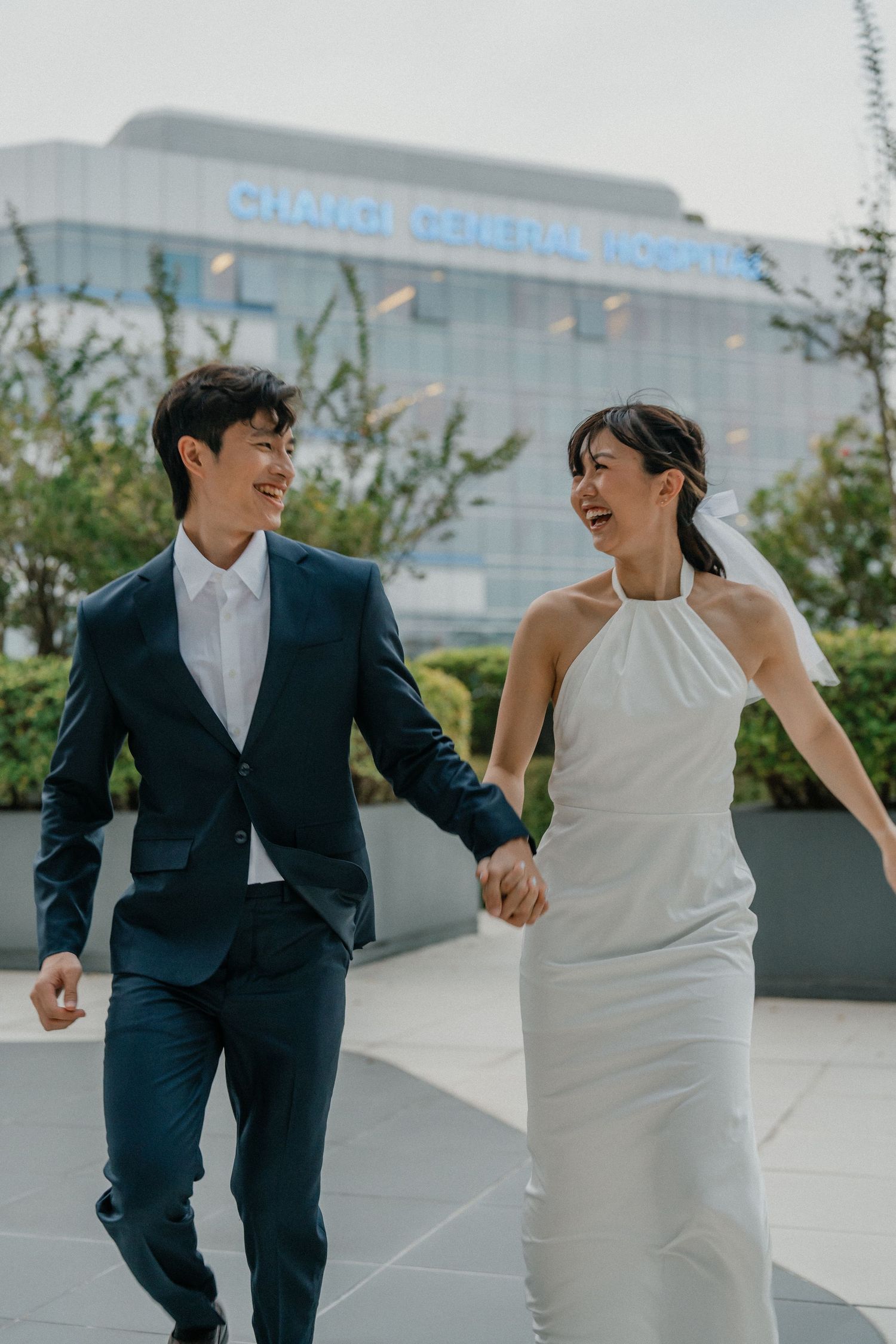 Joyful couple laughing while walking together in wedding attire.