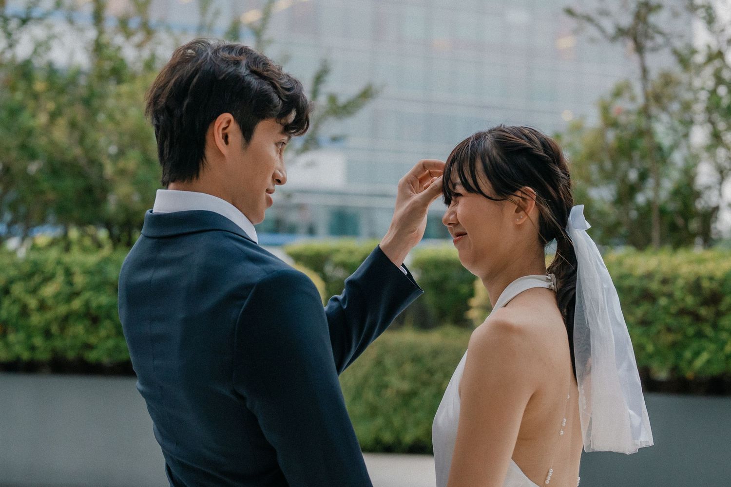 A romantic wedding photoshoot takes place outside Changi General Hospital with greenery in the background.