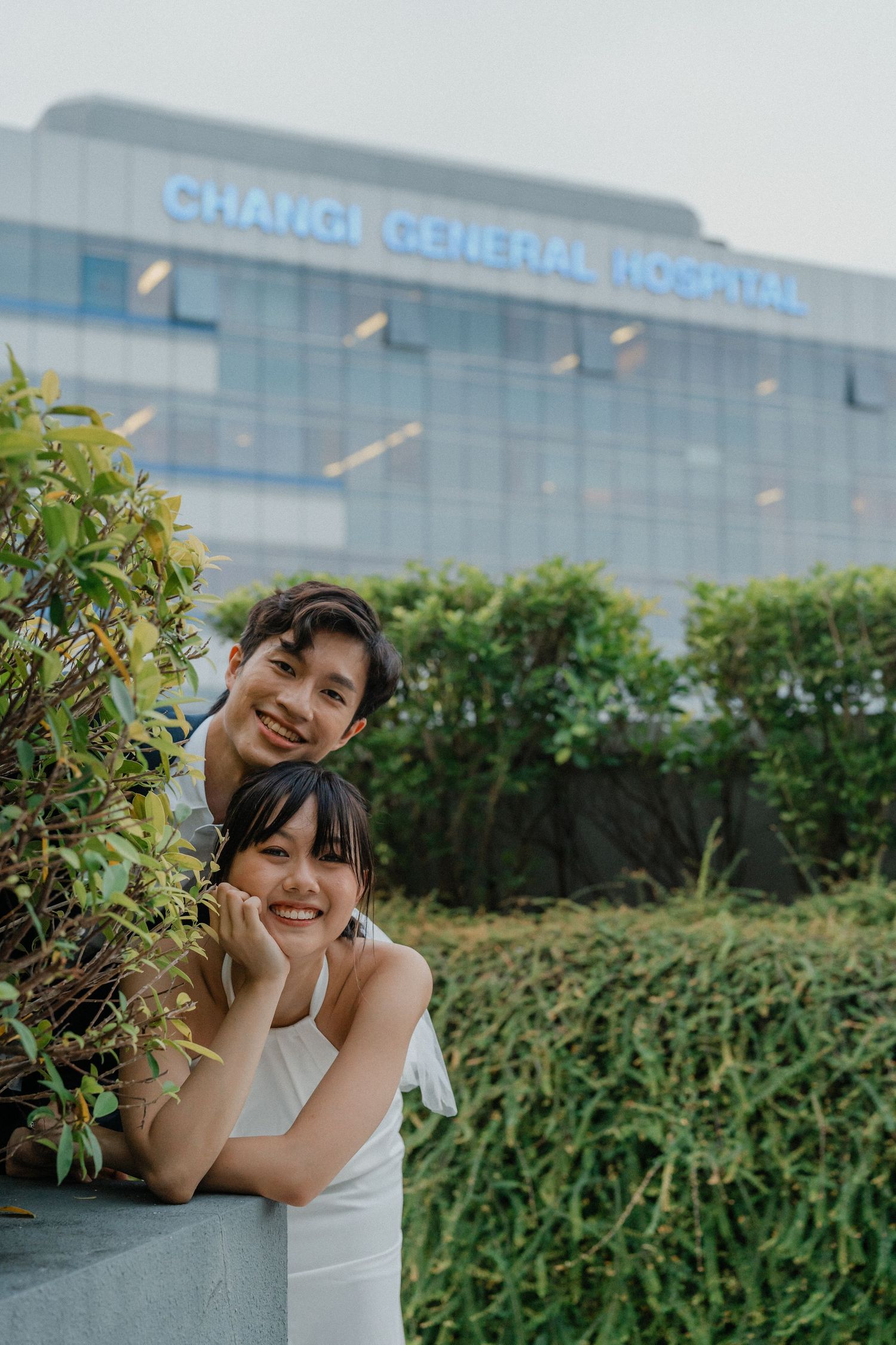 A candid wedding photo showing joy and laughter amid garden landscaping at a hospital.