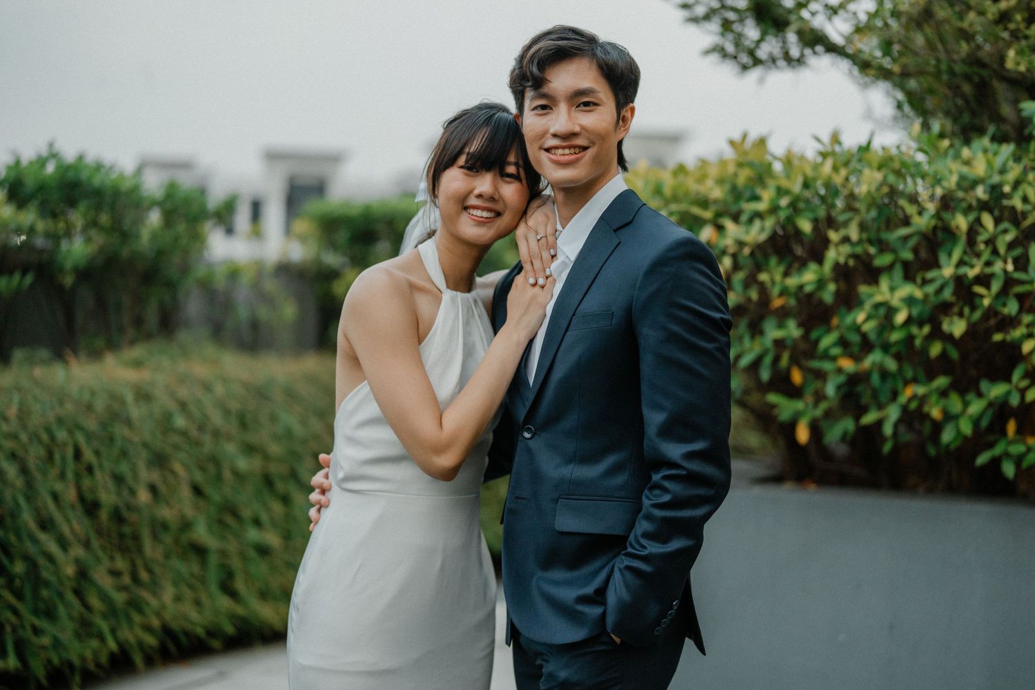 A couple in wedding attire shares an intimate moment together in an outdoor garden setting.