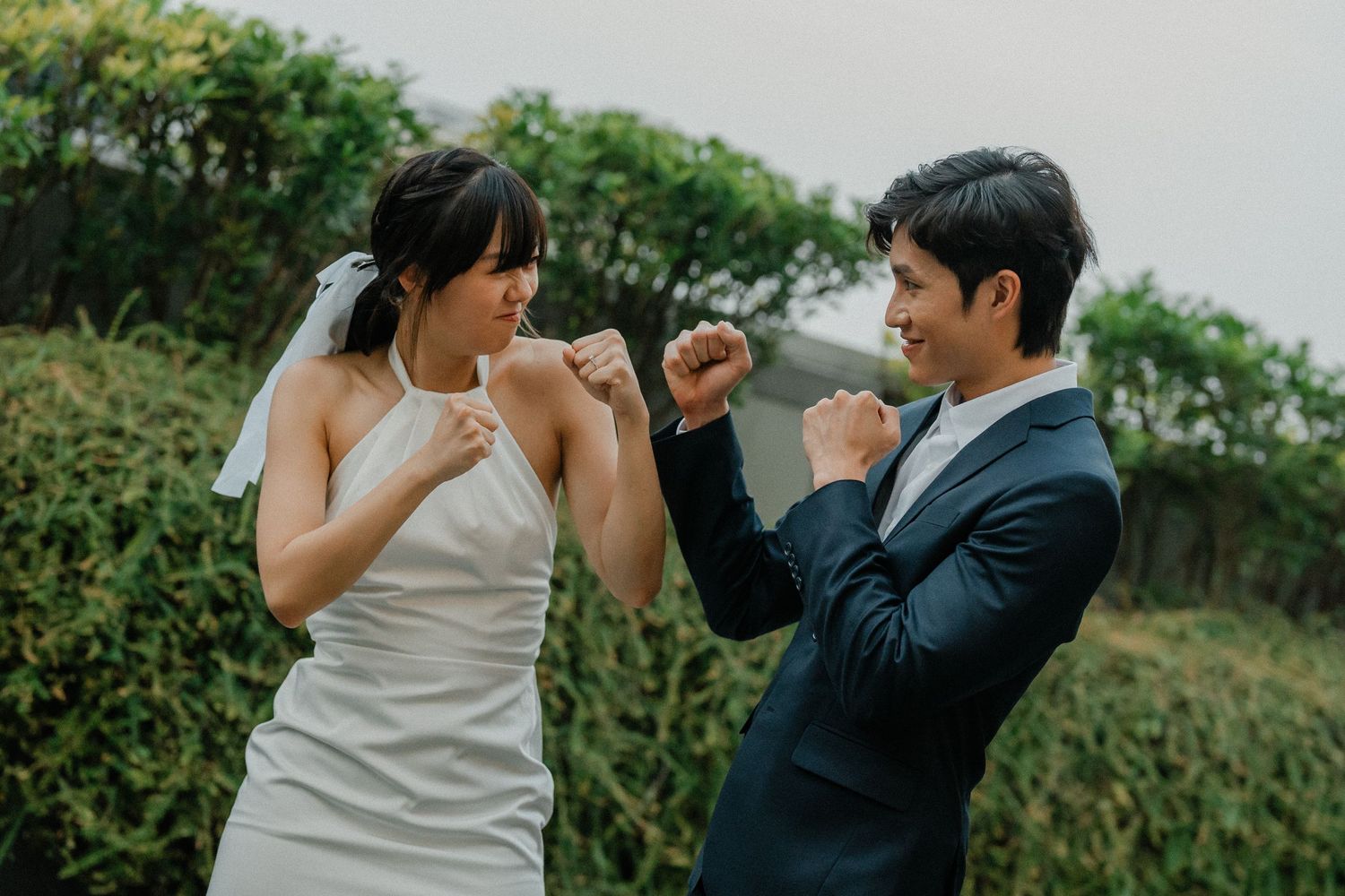 A playful moment between a bride in white and groom in navy during their wedding photoshoot.