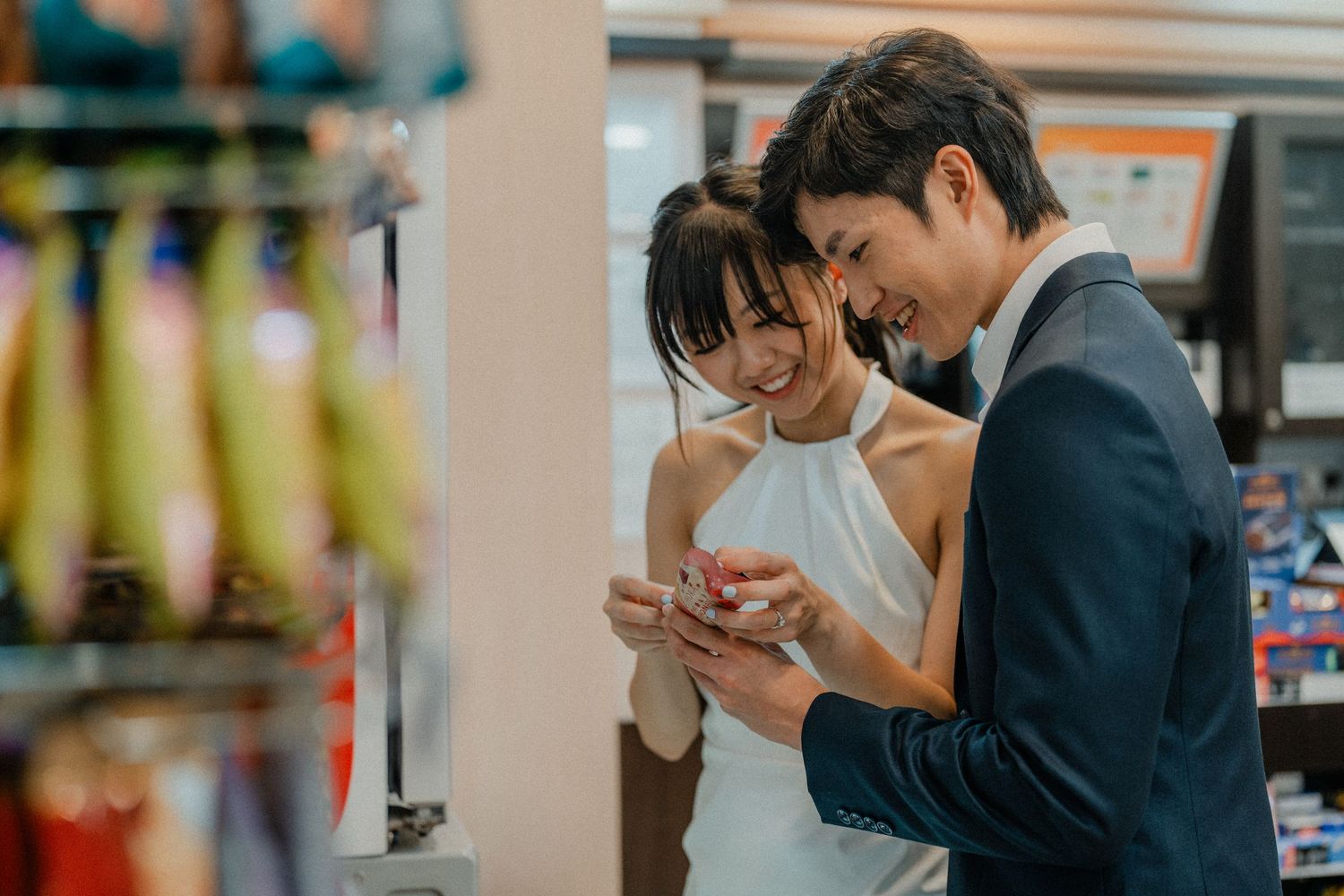 A couple browses their phones together while shopping in a convenience store.