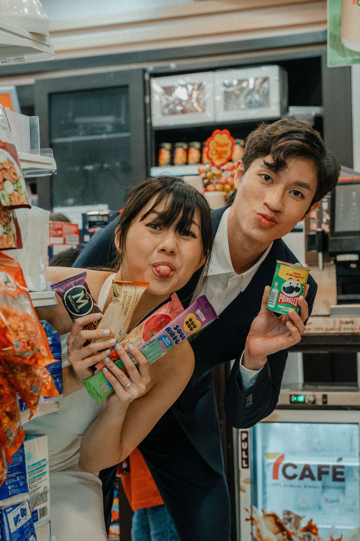 Couple poses with snacks and drinks inside a convenience store.
