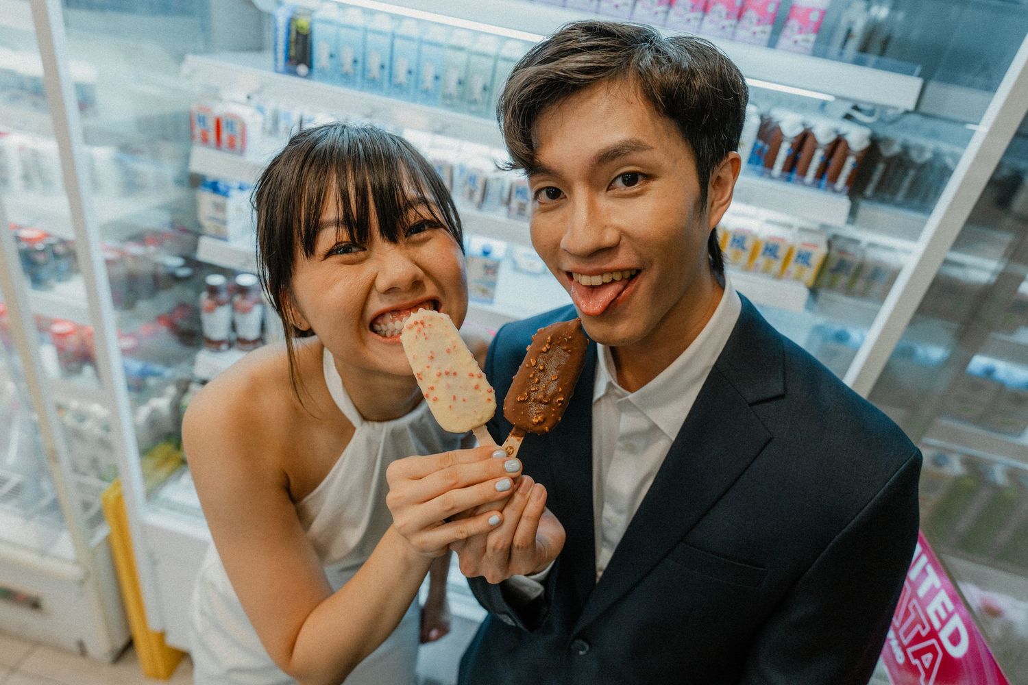 Couple enjoying ice cream treats together in a convenience store.