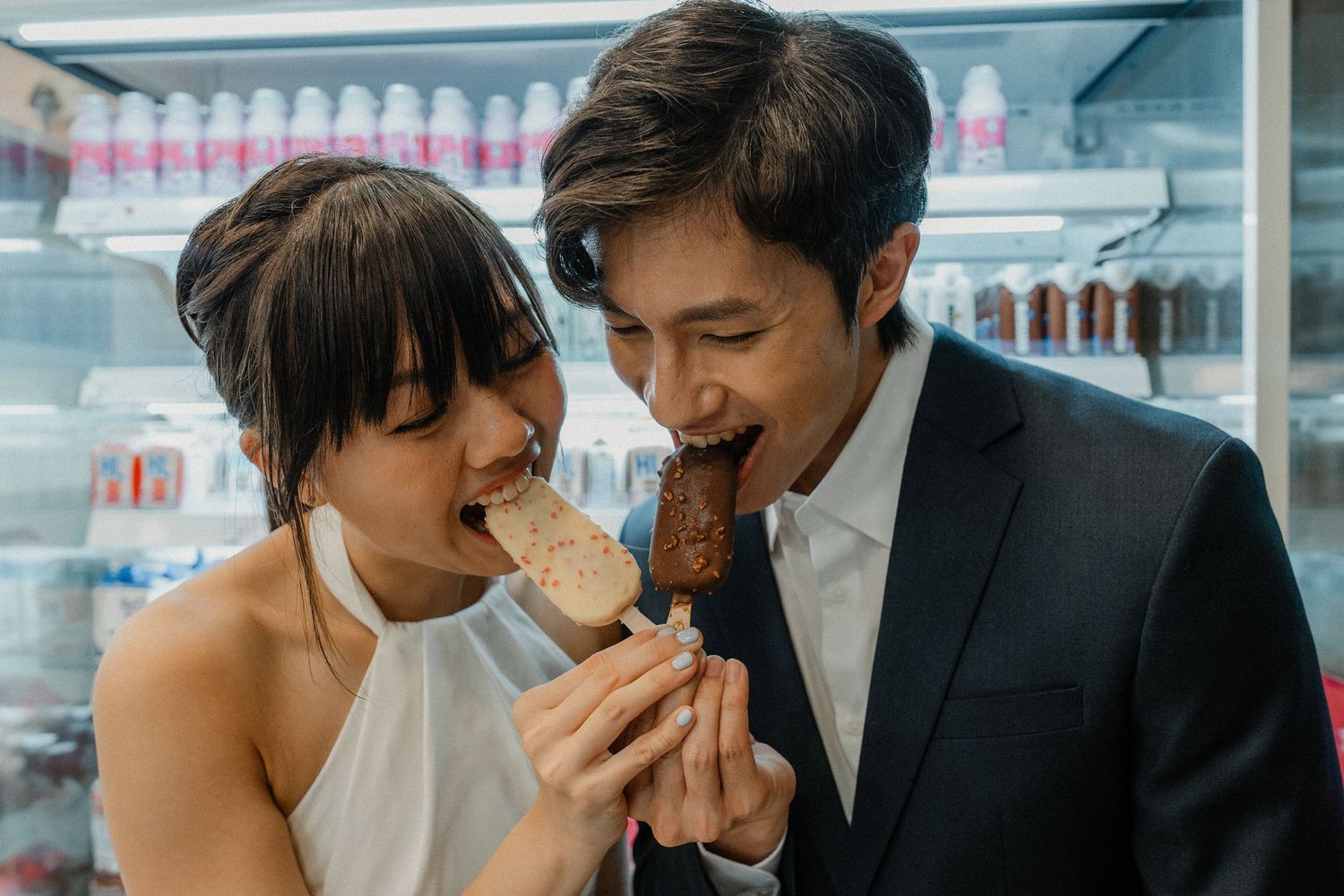 Couple shares a sweet moment while eating ice cream in a store.