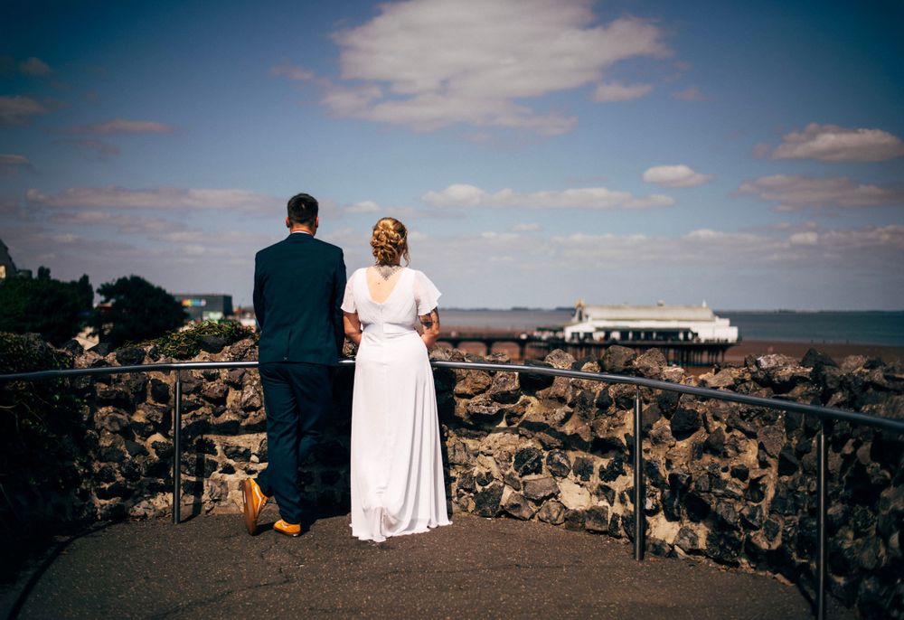 A couple in wedding attire enjoying a scenic overlook while standing on stone walls.
