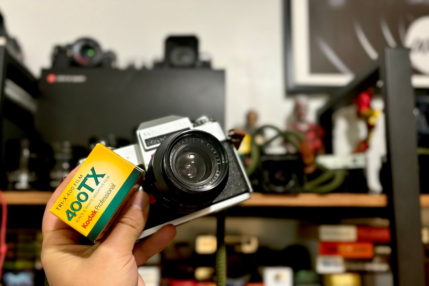 A vintage camera with Kodak film roll displayed on a cluttered shelf.