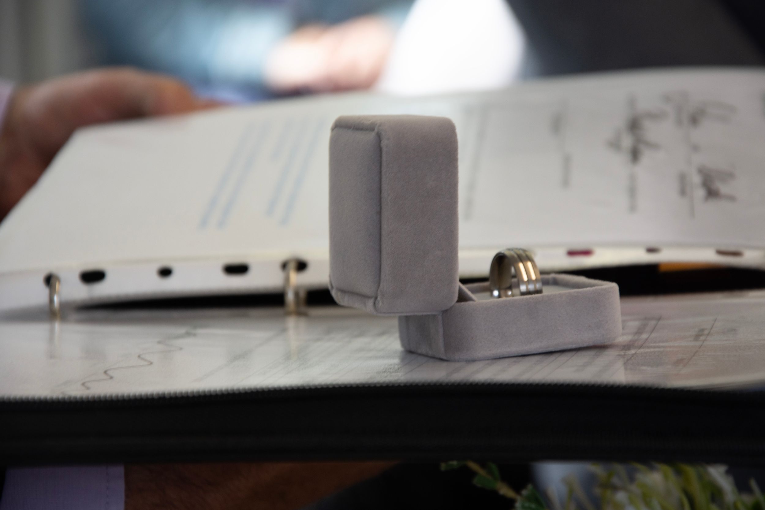 Gray ring box containing wedding bands sits on a document.
