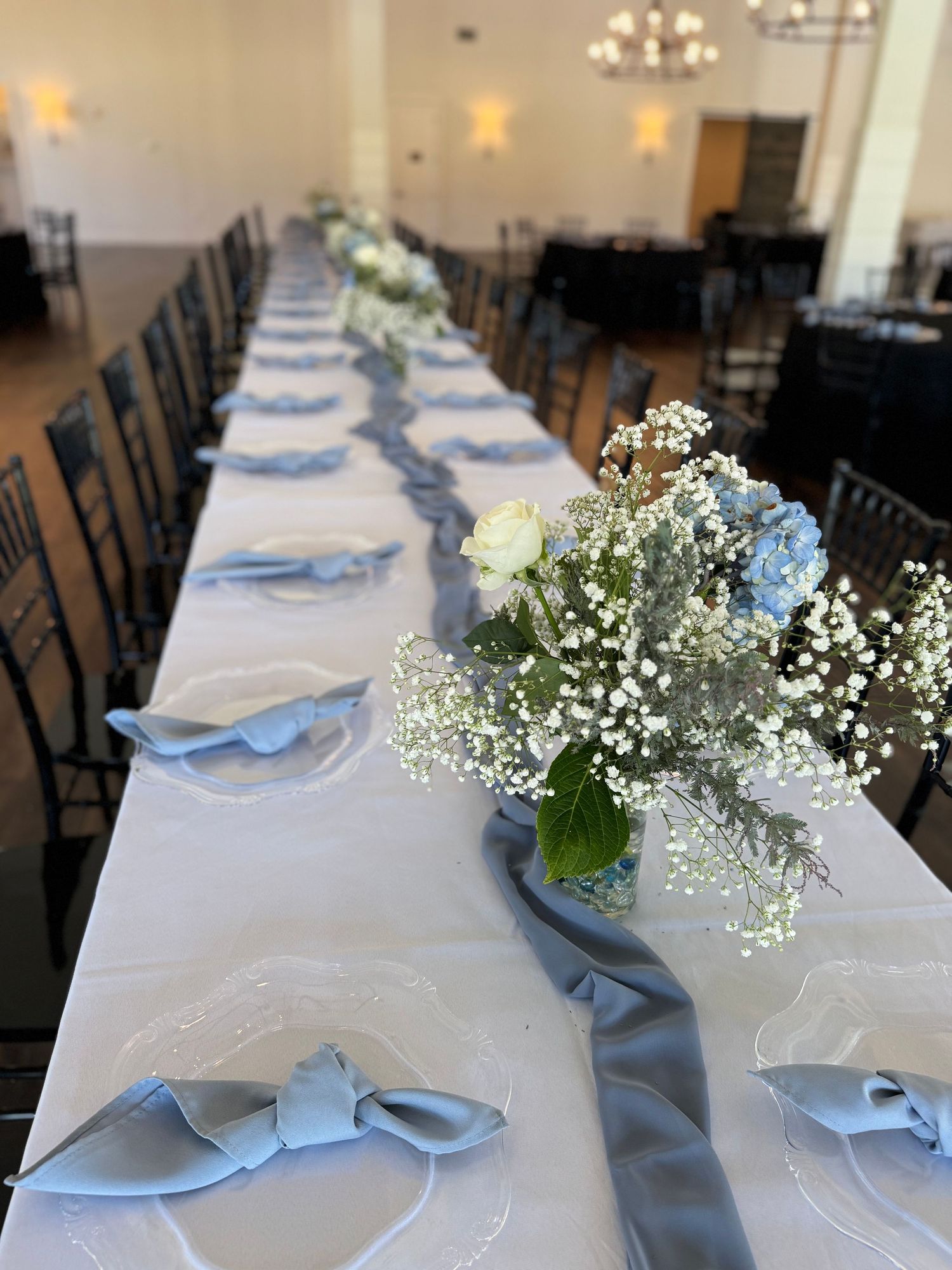Elegant wedding table setting with blue and white decor and delicate floral centerpieces.