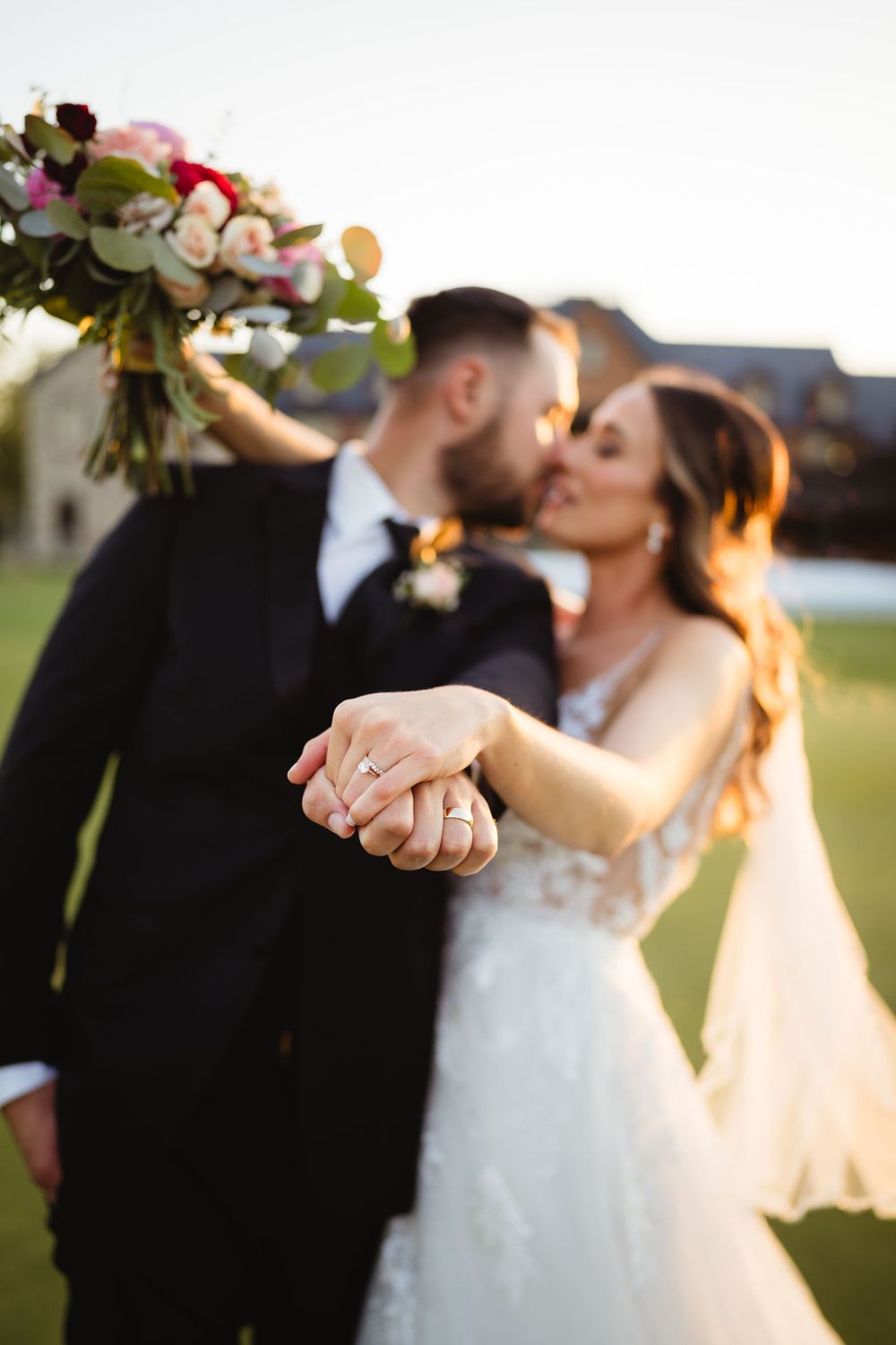 Newlyweds share an intimate moment with bouquet and flowing veil on a golf course at sunset.