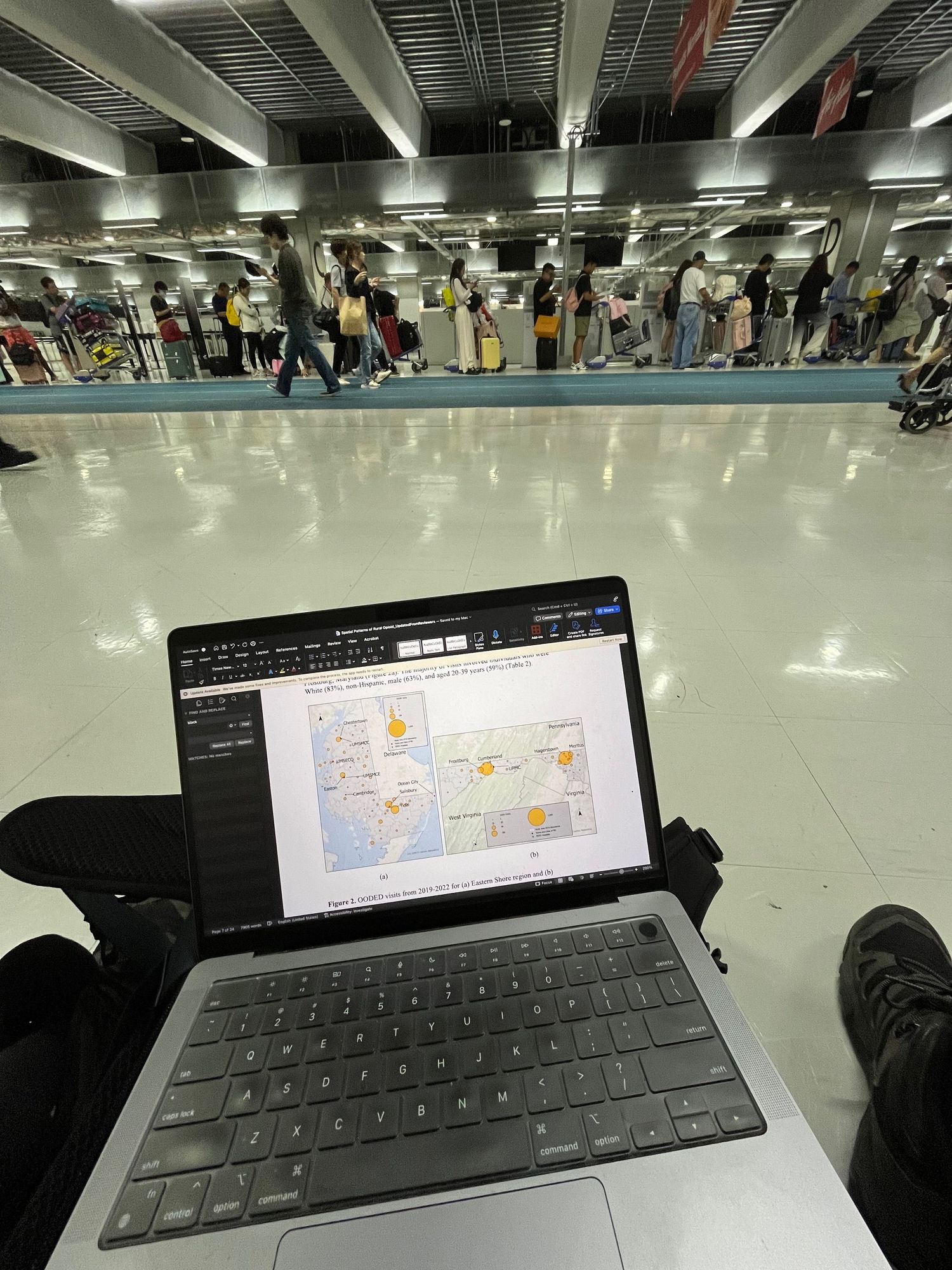 Laptop keyboard and trackpad visible in a large indoor space with reflective floors.