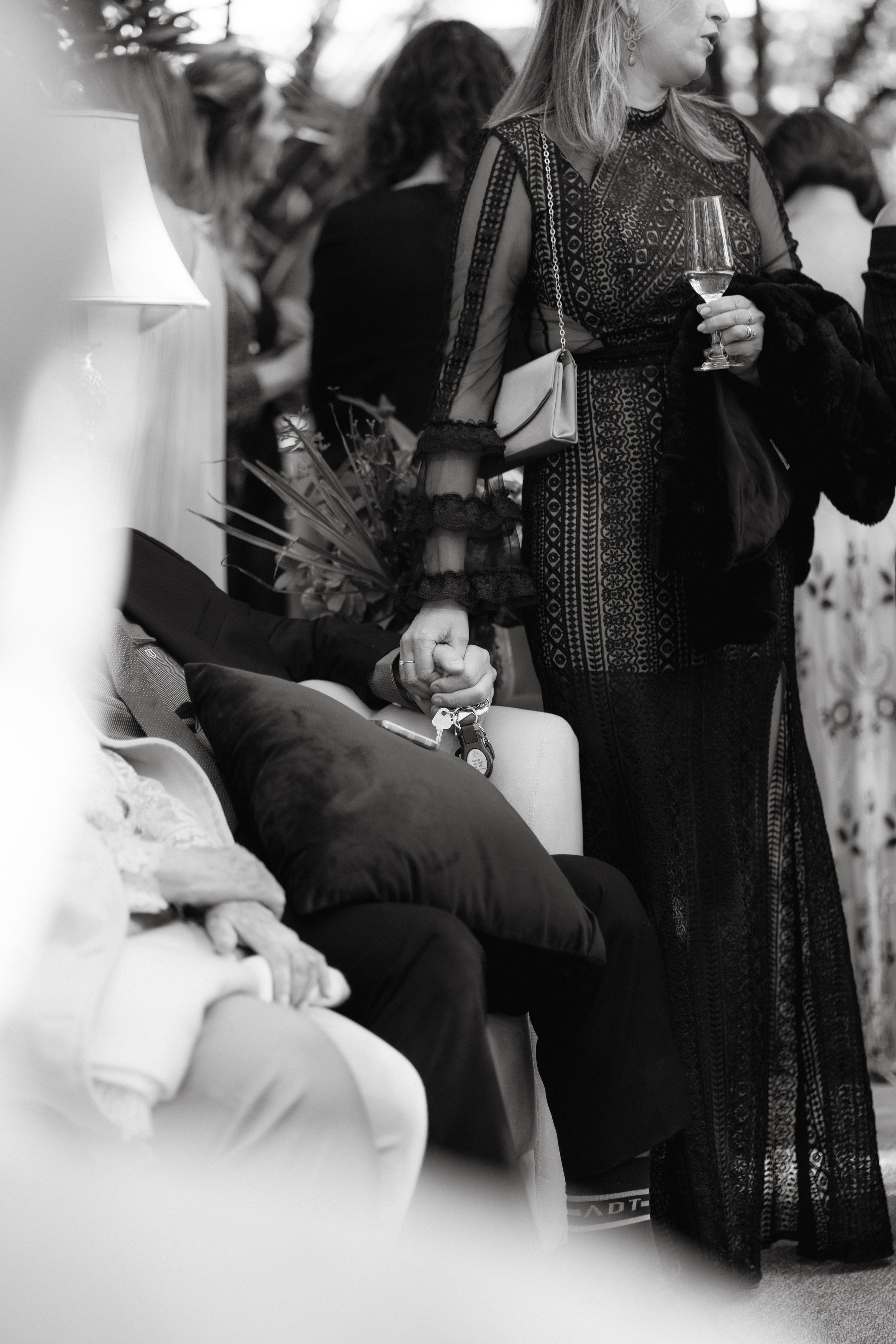 Elegant black and white photo of guests mingling at a formal event with wine glasses.