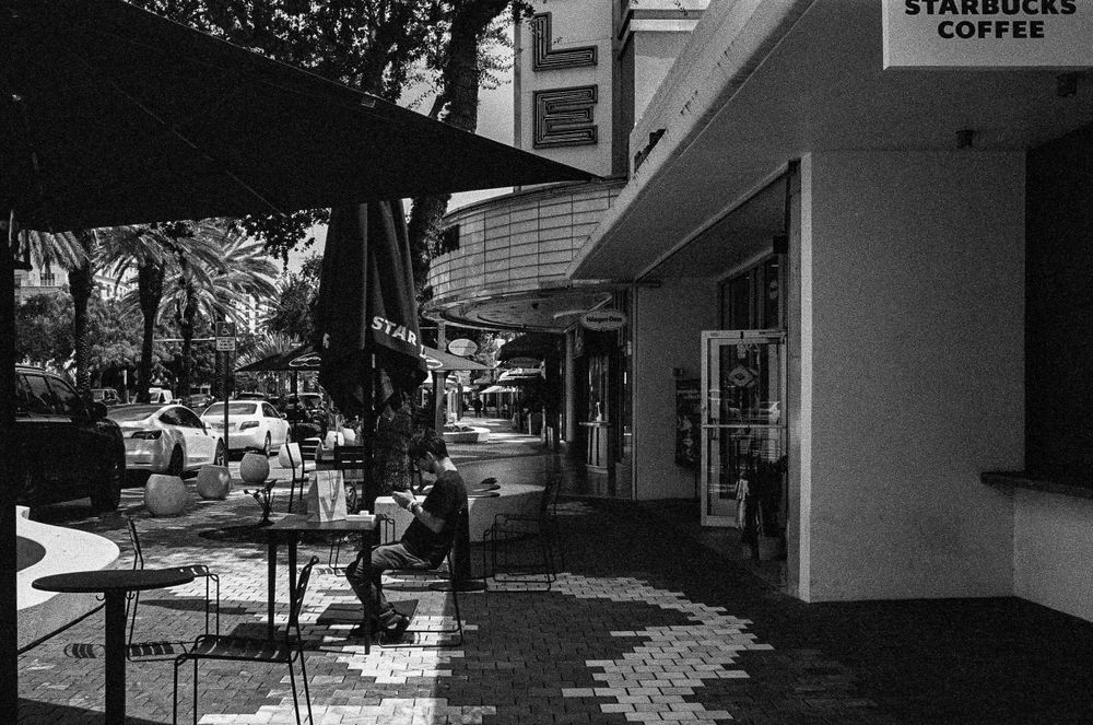 Empty outdoor seating area outside Starbucks Coffee shop in black and white.