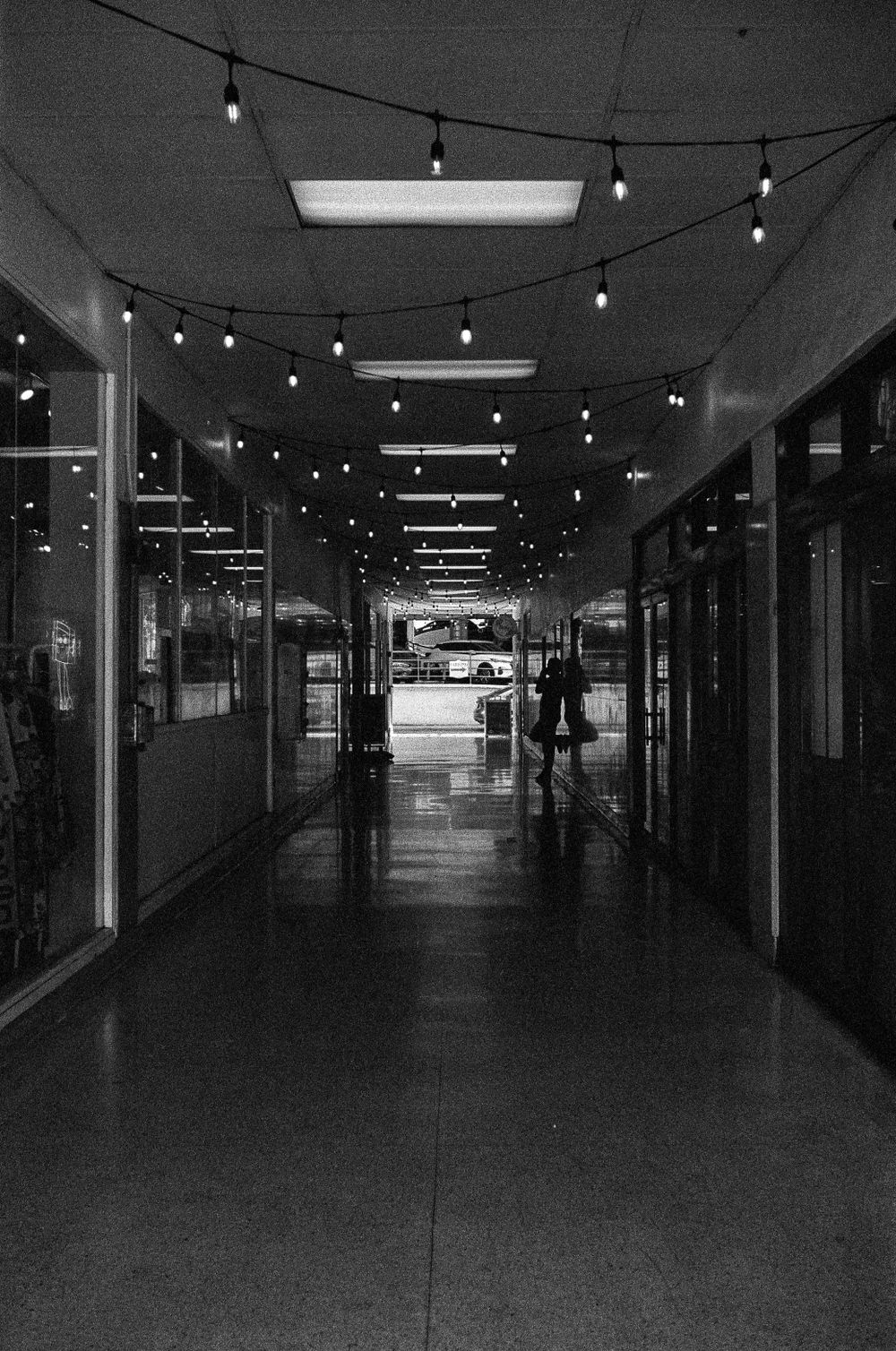 Long indoor corridor with hanging string lights creating depth perspective.