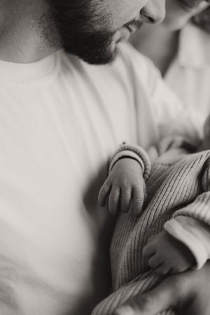Close-up view of small hands wearing a white knit sweater.