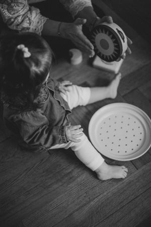 Black and white photo of a small wooden toy on a hardwood floor.