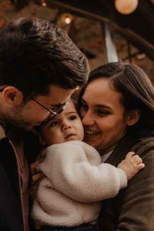 Photo d'une famille lors d'une séance photo. Les parents et l'enfant s'enlacent.