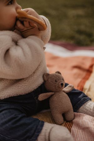 Photo d'un bébé dans un parc lors d'une séance famille. Il joue avec des jouets pour bébé.