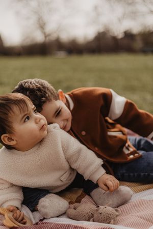 Photo de deux enfants assis dans l'herbe dans un parc lors d'une séance famille