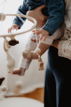 Small hands reaching for hanging white decorative ornaments.