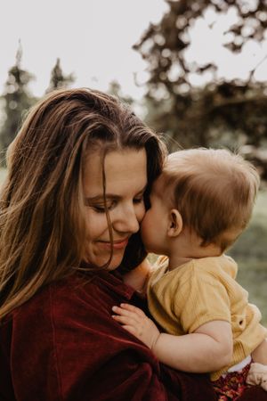 Photo d'une femme et de son enfant. Leurs têtes sont proches l'une de l'autre, ils se font un câlin