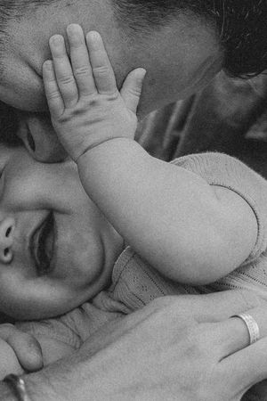Black and white image of small hands resting on soft fabric.