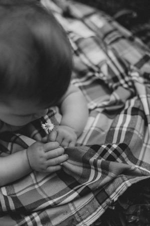Close-up of small hands touching a plaid blanket pattern.