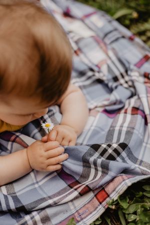 Photo d'un bébé qui tient une fleur dans ses mains.