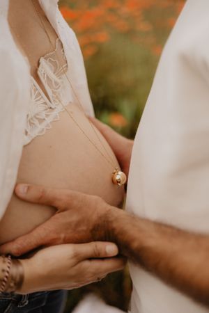 Photo d'un ventre de femme enceinte. Le futur papa pose ses mains sur le ventre.