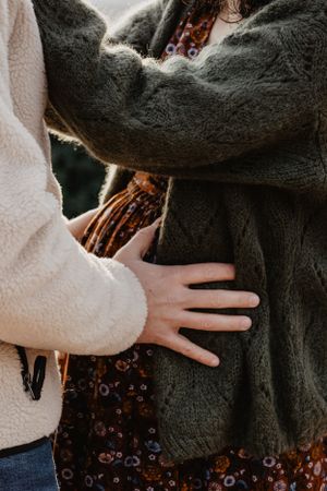 Photo d'un couple attendant leur futur enfant. L'homme pose ses mains sur le ventre de la femme.