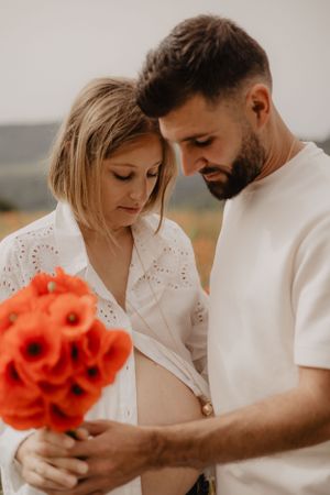 Photo d'un couple dans un champ de coquelicot pour une séance grossesse.