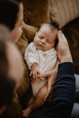Photo d'une séance naissance. Les deux parents tiennent le bébé qui dort dans leurs bras
