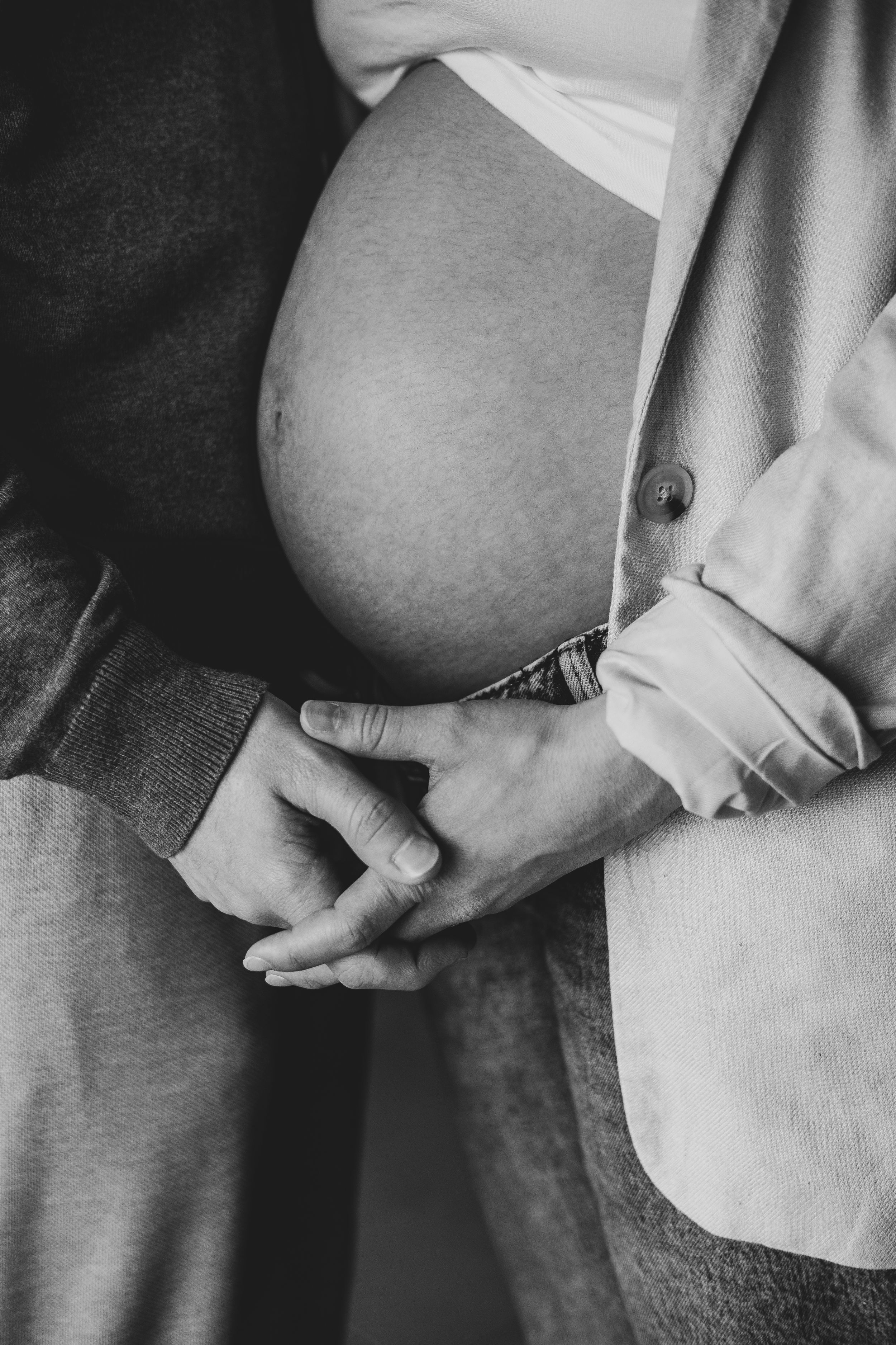 Photo en noir et blanc d'un couple qui se tiennent la main. La femme est enceinte.