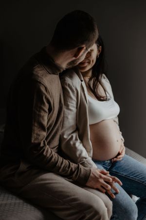 Photo d'un couple pour une séance grossesse. Ils sont assis et se regarde tendrement.