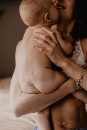 Photo d'un bébé nu dans les bras de sa mère lors d'une séance allaitement.