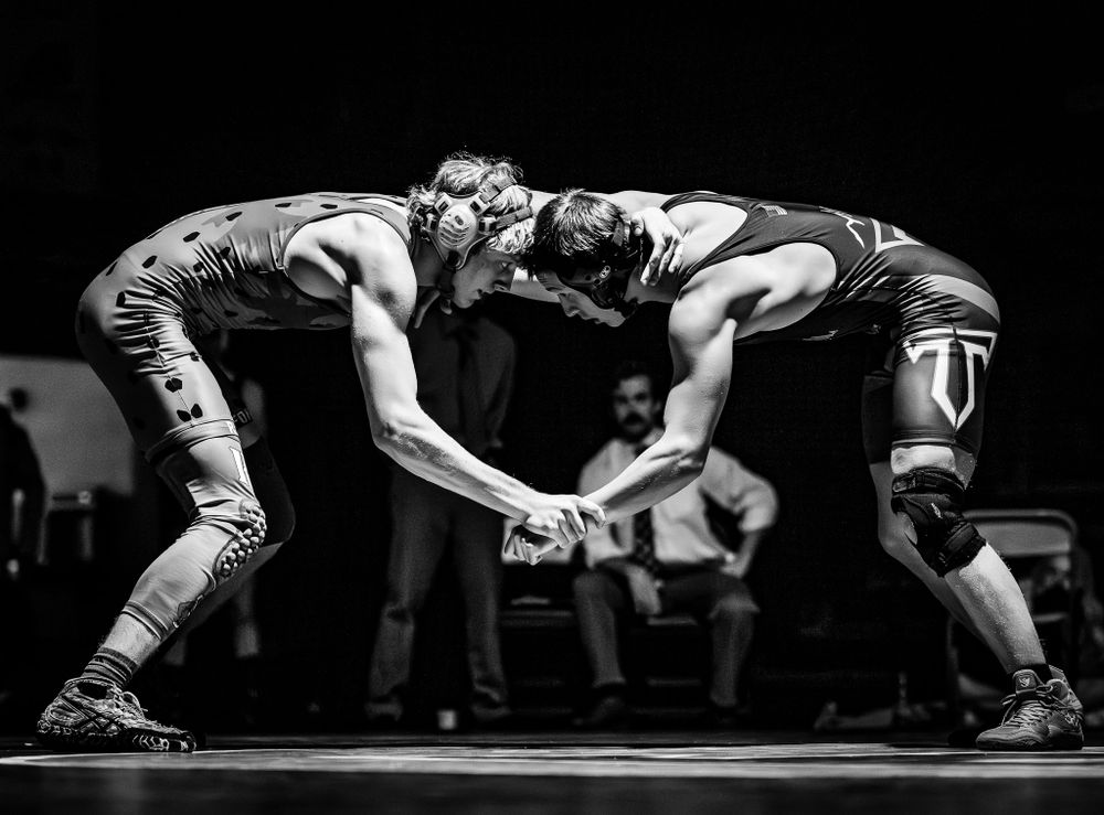 Two wrestlers locked in intense grappling match on competition mat.