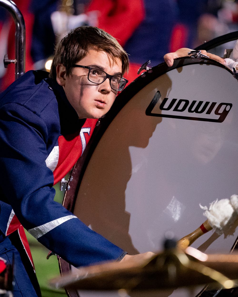 Band member playing large Ludwig bass drum during sporting event.