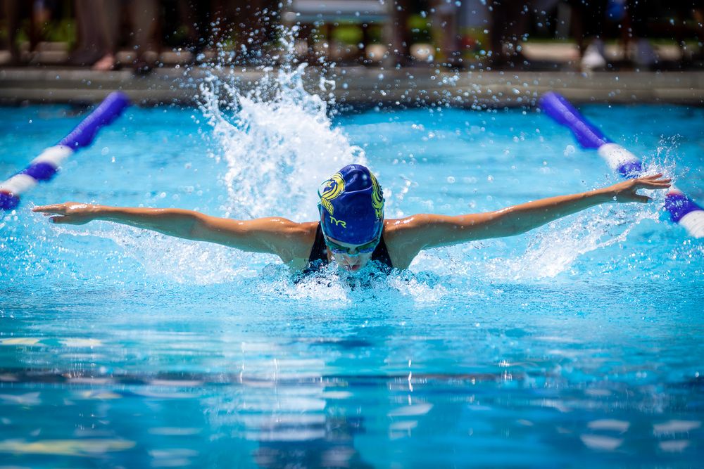 Swimmer performing butterfly stroke with dramatic water splash in competition pool.