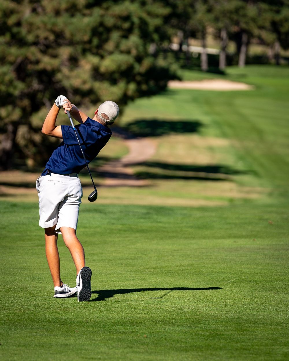 Golfer following through on swing on pristine fairway.
