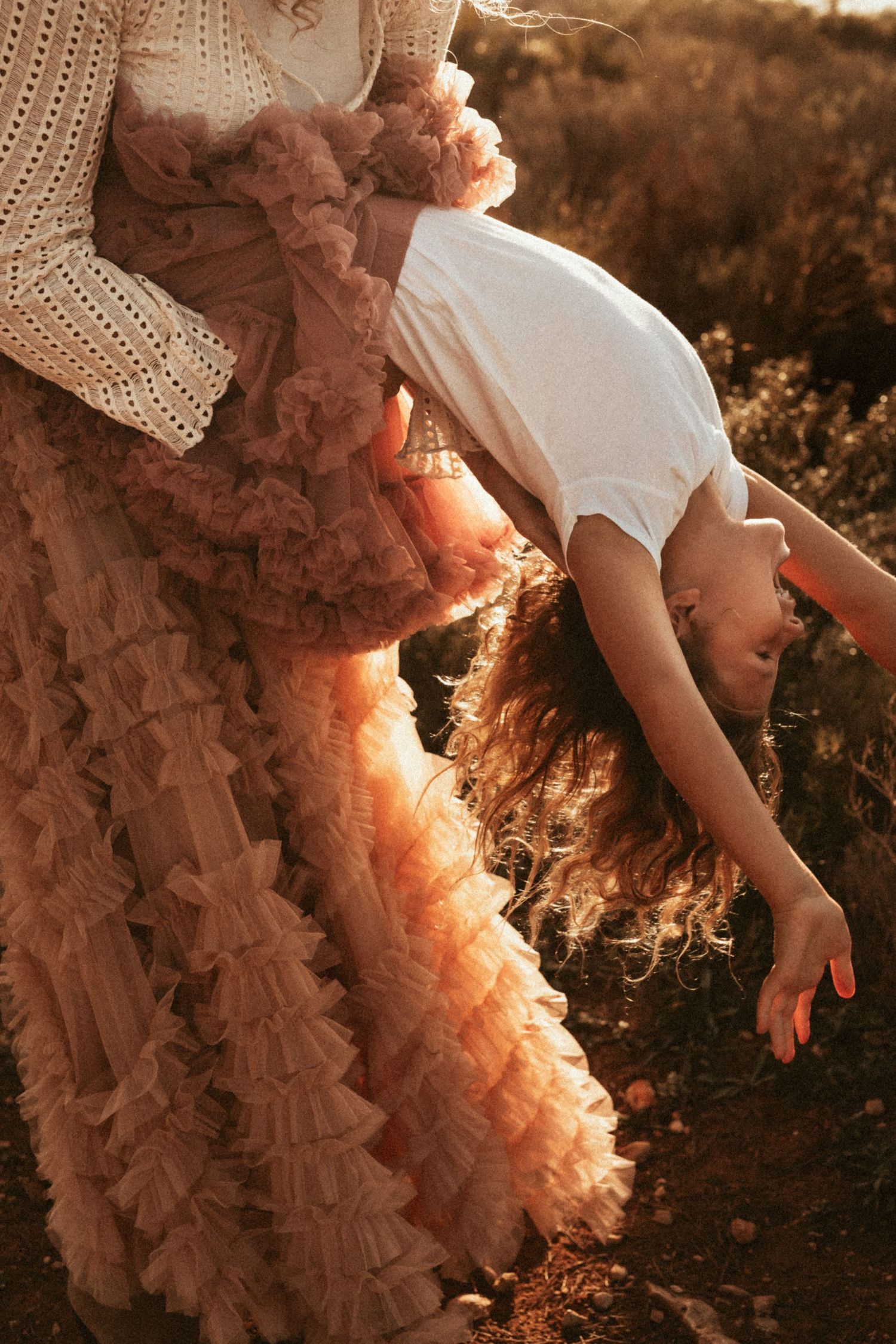 Dreamy backlit portrait in Javea  of person in flowy peach ruffled dress bending backwards gracefully at sunset in nature.Javea Photographer