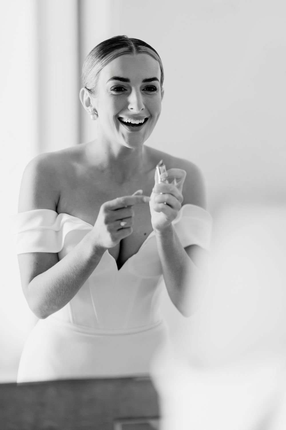 Black and white portrait of someone in an off-shoulder white dress expressing joy and laughter.