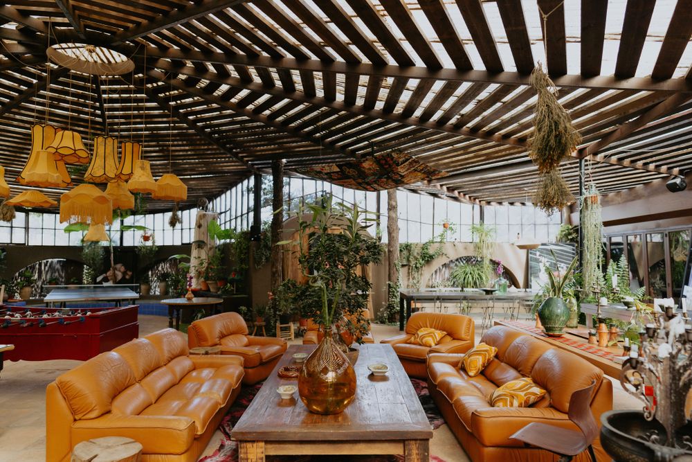Luxurious lounge area with tan leather furniture and yellow pendant lights under a wooden slatted ceiling.