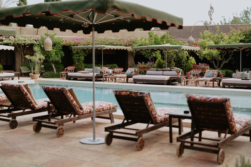 Luxurious poolside lounge chairs with umbrellas at an upscale resort spa featuring brown cushions and tranquil ambiance.