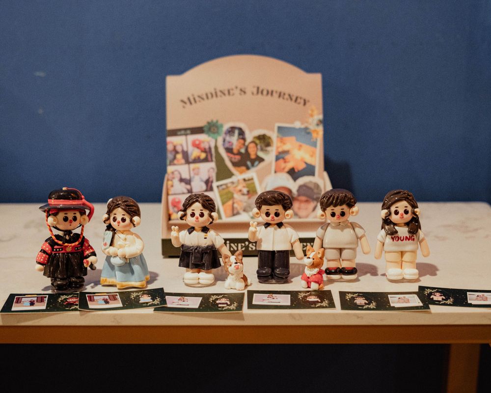 Collection of cute cartoon figurines displayed with cards under a 'Sinoera's Journey' sign.