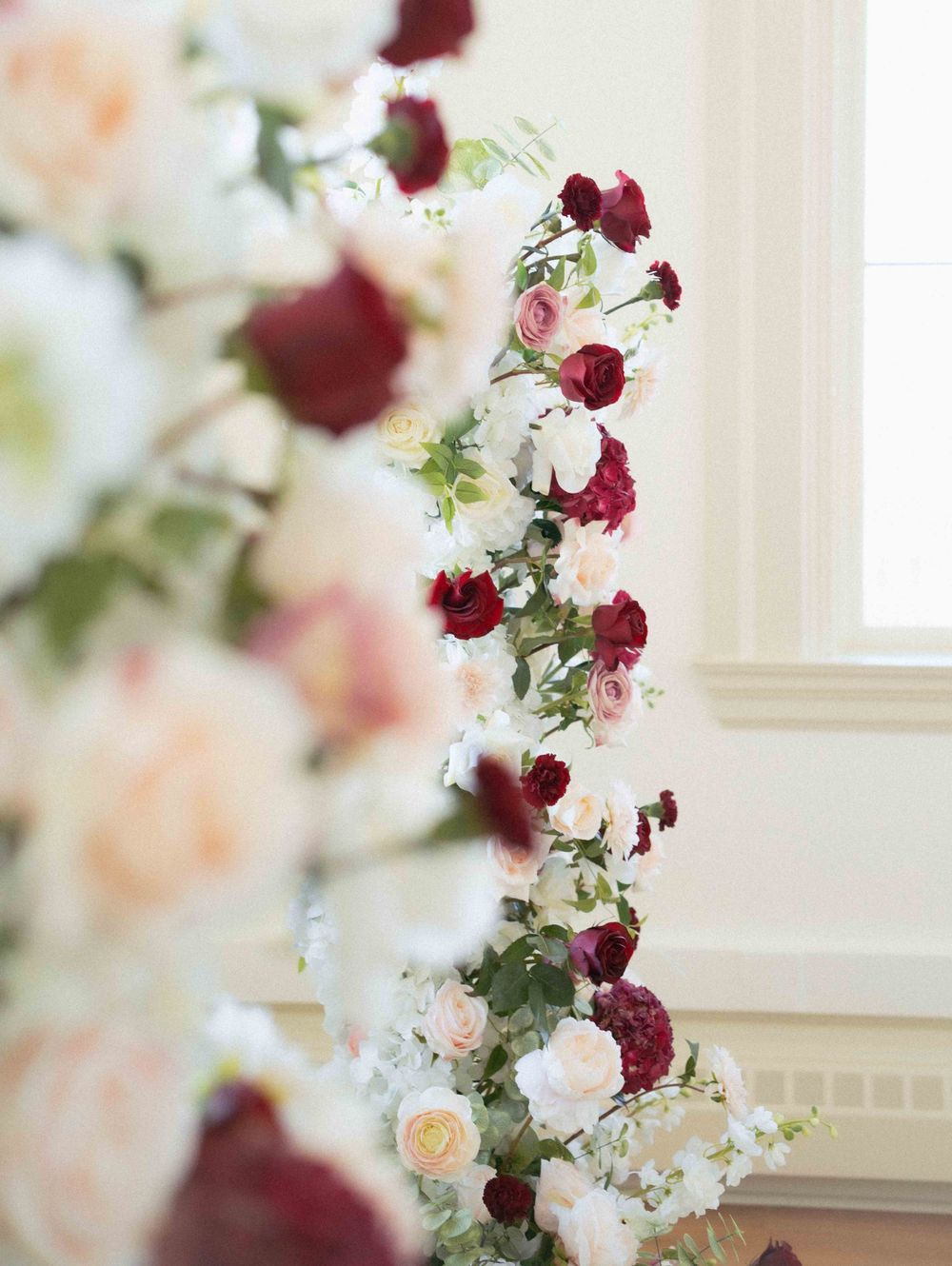 Detailed view of cascading floral arrangement with red and white flowers against white walls. Location: Events at Ethereal Courthouse Square