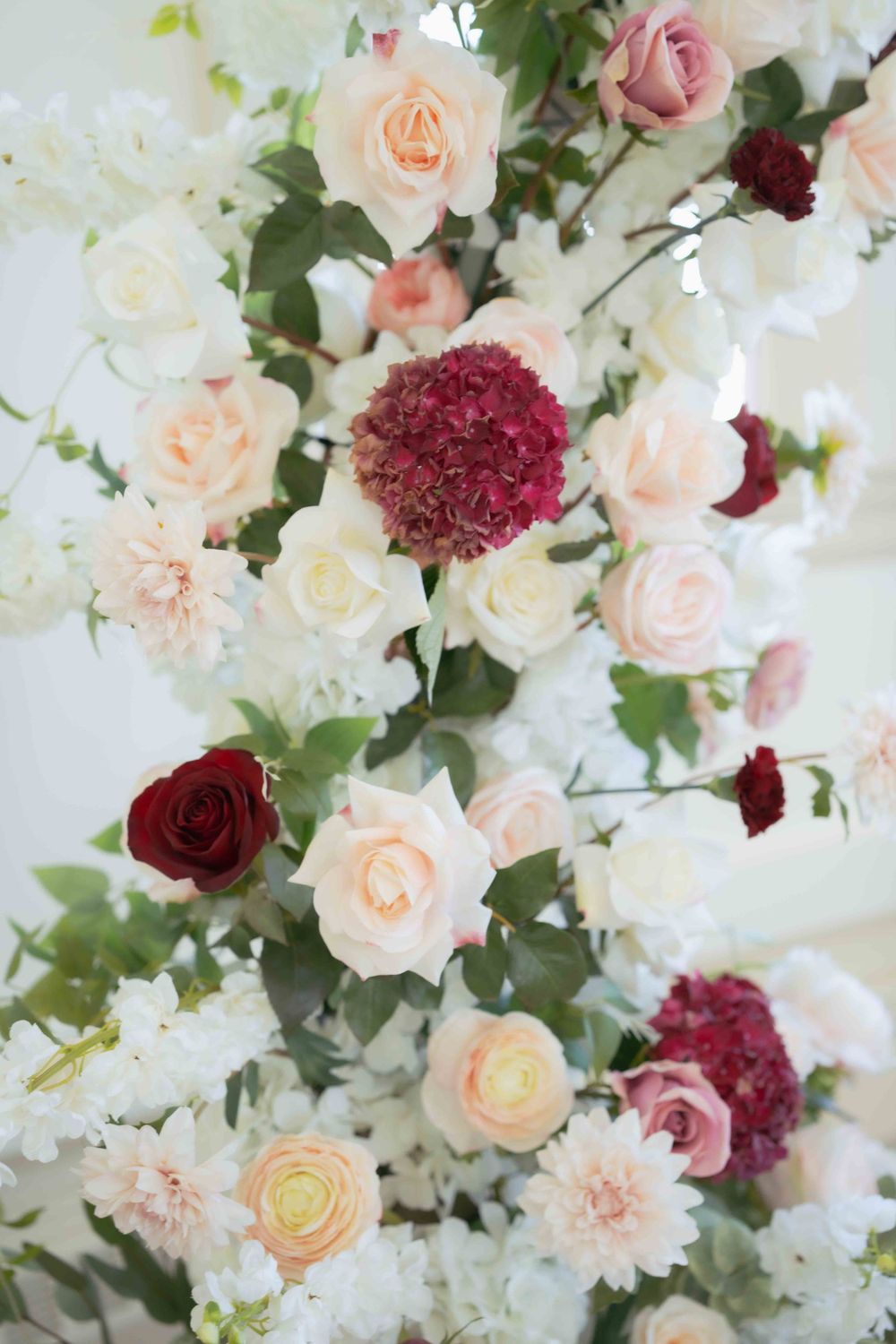 Lush floral arrangement combining blush roses, white flowers, and deep burgundy blooms. Location: Courthouse Square Woodstock, IL.